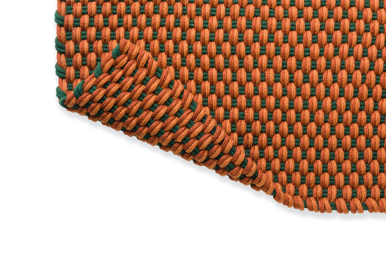 Angle of rug corner showing tight braided weave and stitched edge finish

