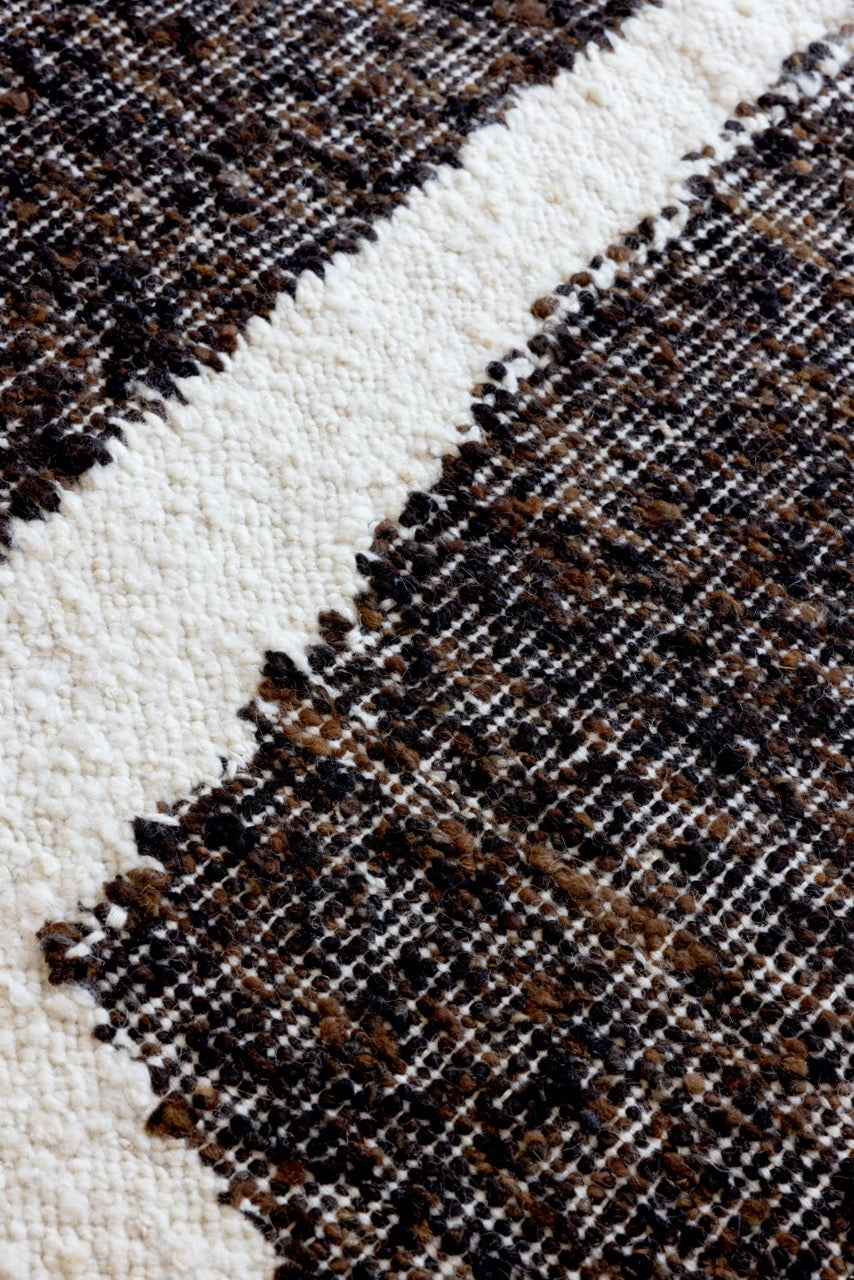Close-up of carved pile relief in chocolate and cream hand-tufted wool rug