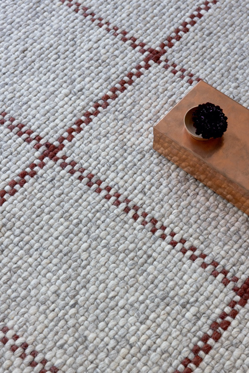Detail of handwoven check pattern in stone, ash grey, and muted red