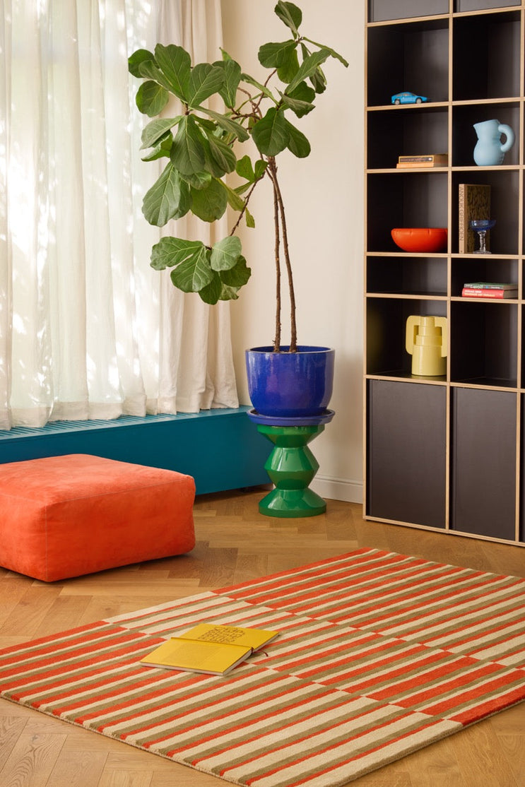 Brink & Campman Decor Pilar Coral rug in coral red with olive green and cream stripes, shown in an interior