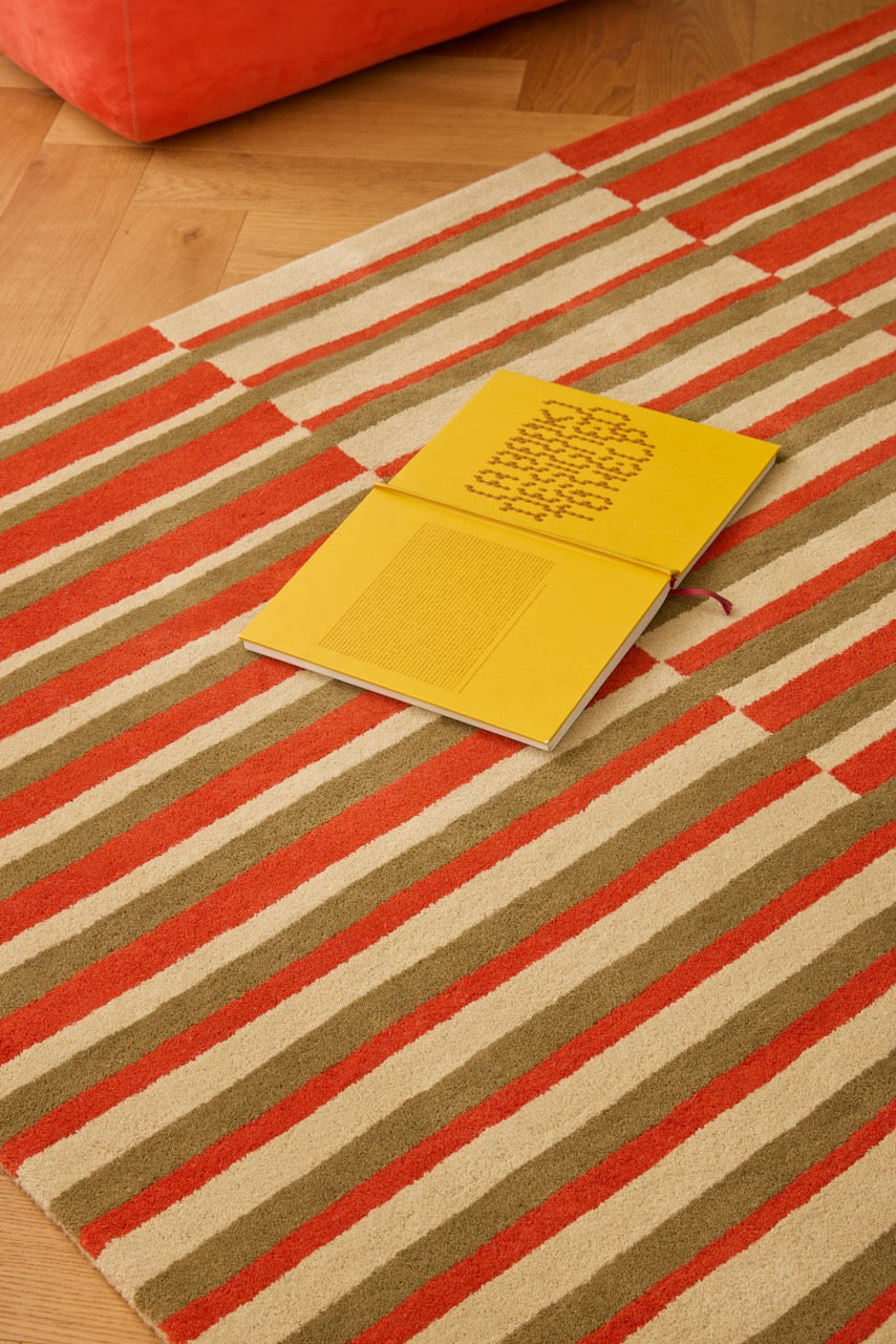 Brink & Campman Decor Pilar Coral rug in coral red with olive green and cream stripes, shown in an interior, second view