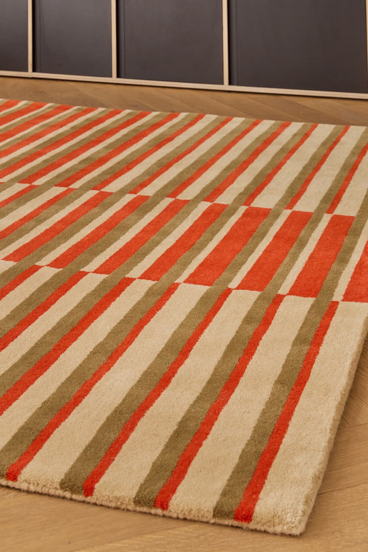 Brink & Campman Decor Pilar Coral rug in coral red with olive green and cream stripes, shown in an interior, third view