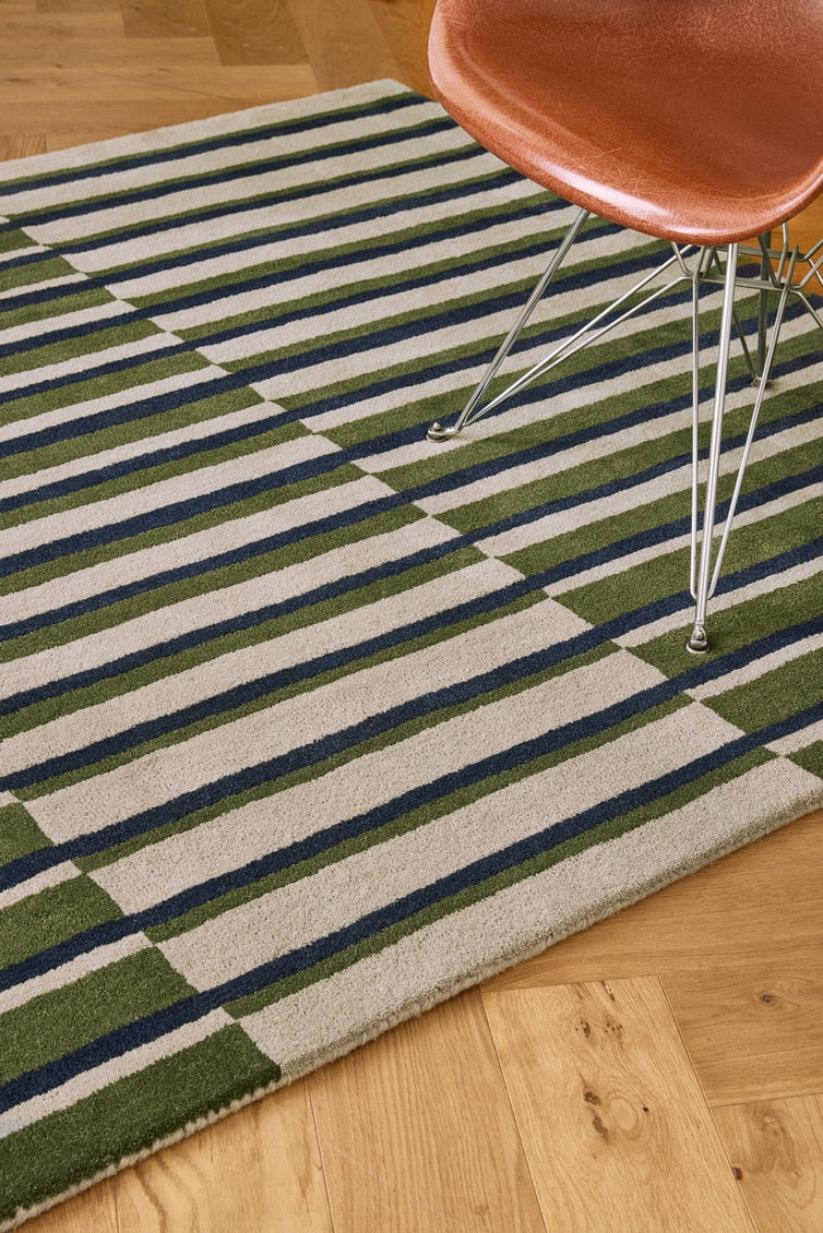 Brink & Campman Decor Pilar Moss rug in moss green with navy blue and light grey stripes, shown in an interior, second view
