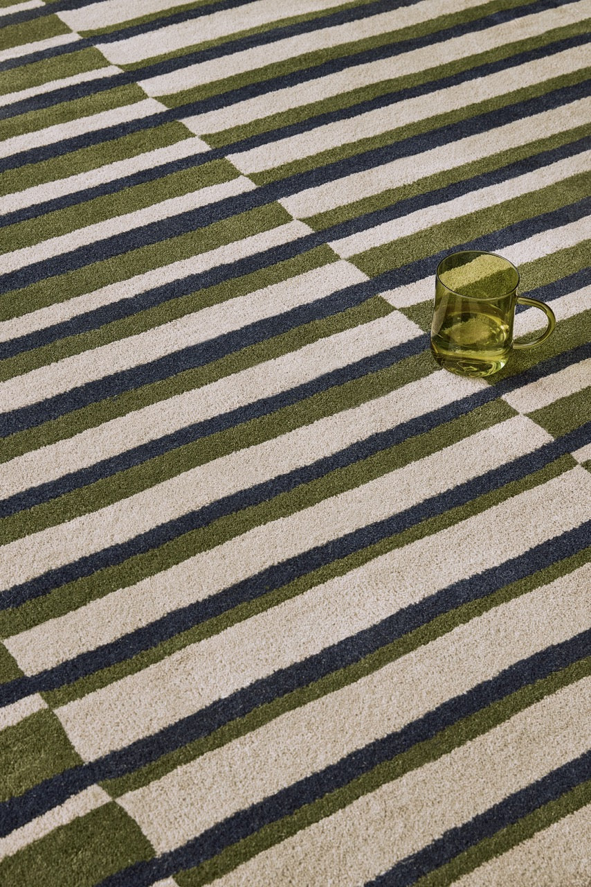 Brink & Campman Decor Pilar Moss rug in moss green with navy blue and light grey stripes, shown in an interior, third view