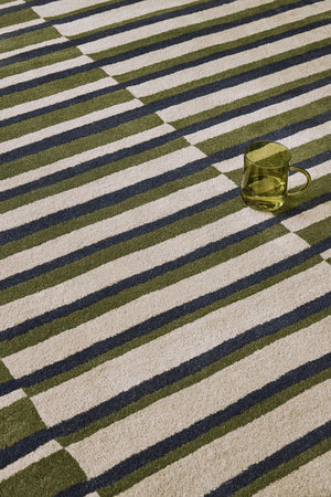 Brink & Campman Decor Pilar Moss rug in moss green with navy blue and light grey stripes, shown in an interior, third view