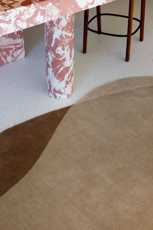 Abstract design rug placed under a dining table with oak chairs

