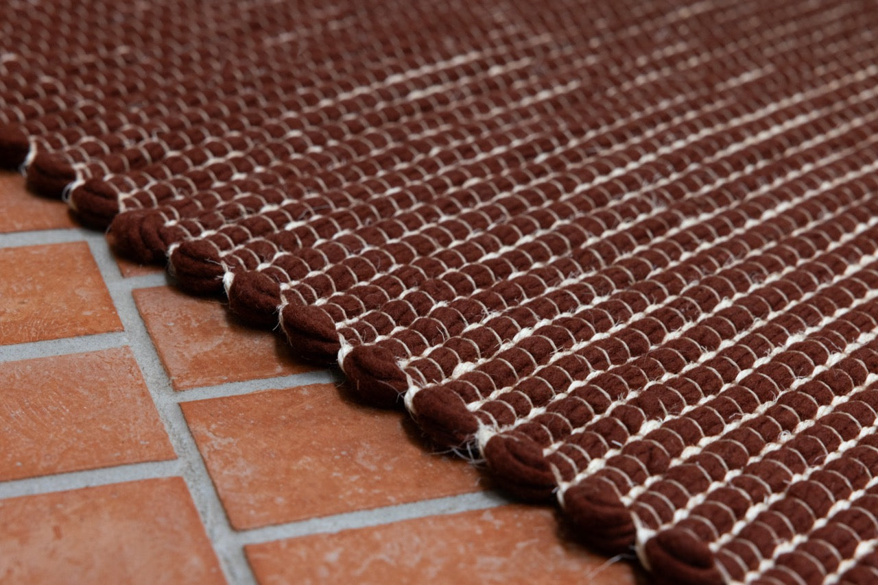 Close-up of brick red hand-carved wool pile with sculptural relief
