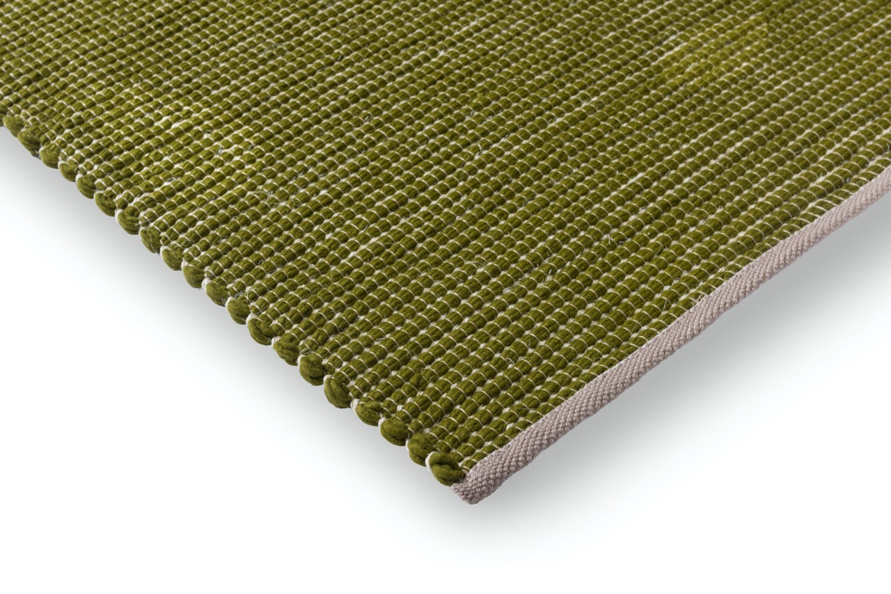 Corner view showing flatwoven surface and hand-finished stitching in soft green
