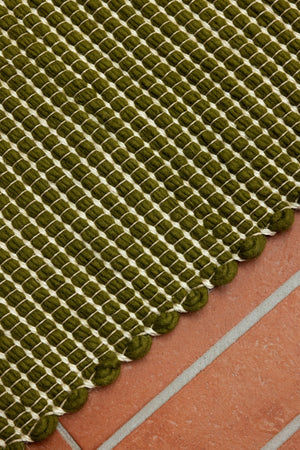 Close-up of green wool and jute weave with ivory edge stitch and soft texture