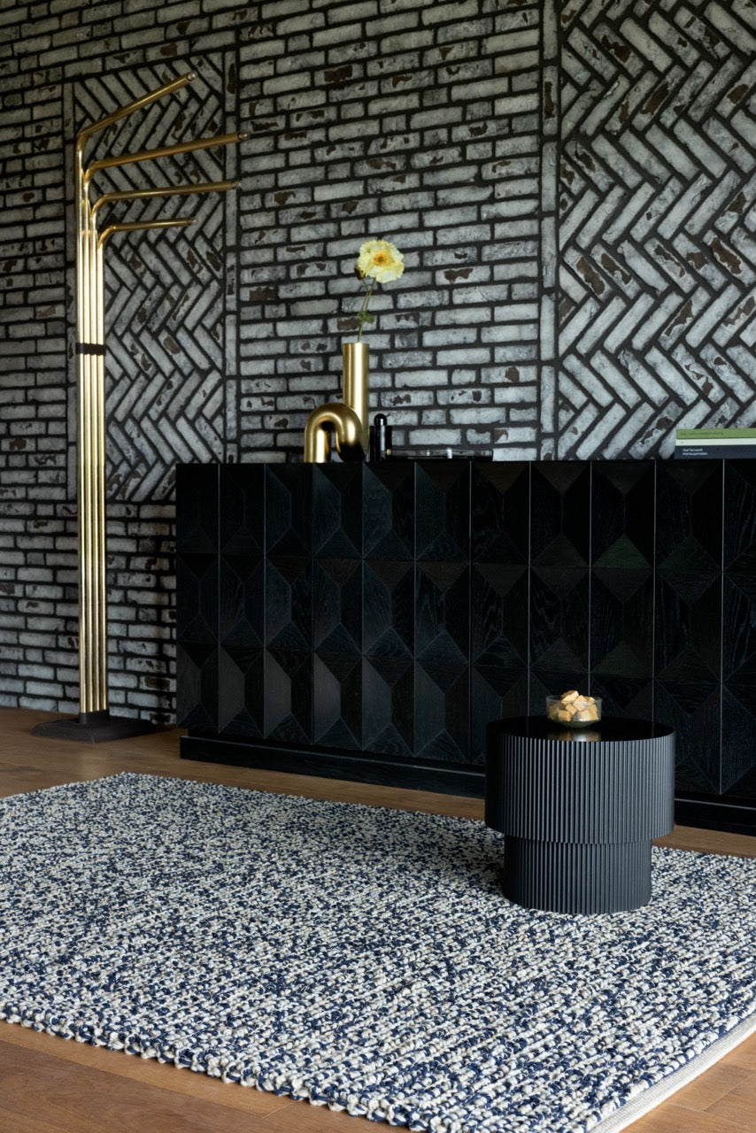 Brink & Campman Nest Ink rug styled in a dark-toned lounge with soft upholstery and natural wood