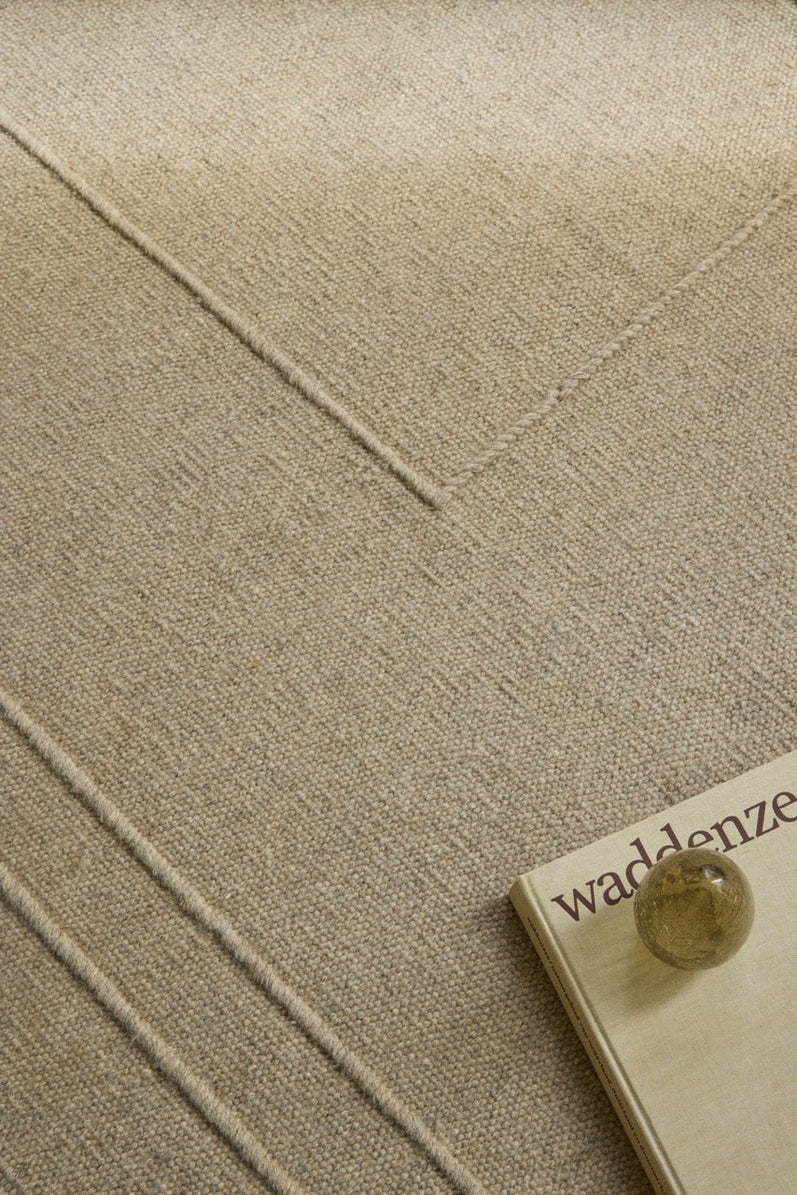 Brink & Campman Senso Planes Natural rug in sand beige with overlapping rectangles in relief, shown in an interior, second view