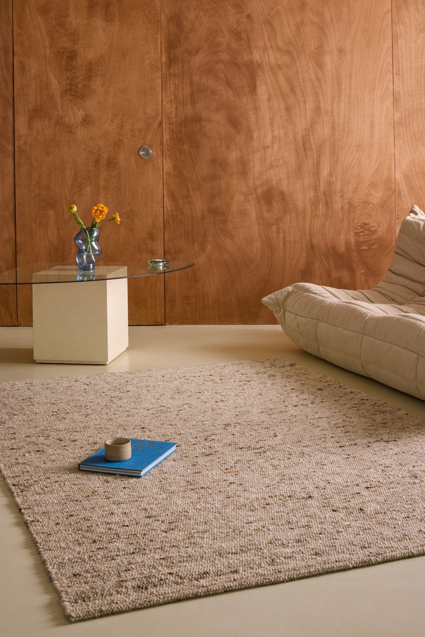 Brink & Campman Sober Natural rug in oatmeal beige and cream with brown flecks, shown in an interior