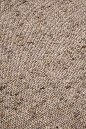 Brink & Campman Sober Natural rug in oatmeal beige and cream with brown flecks, shown in an interior, third view