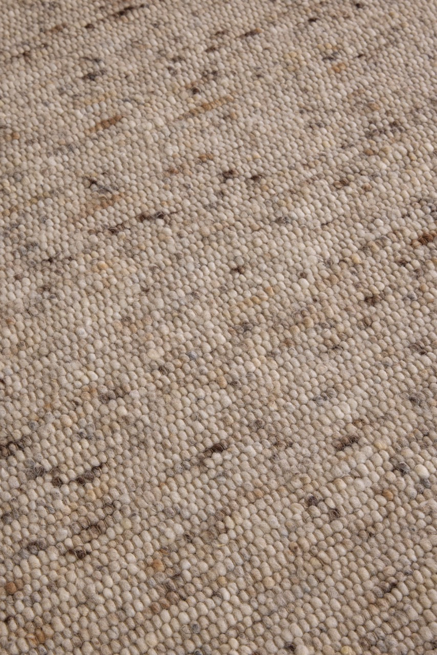 Brink & Campman Sober Natural rug in oatmeal beige and cream with brown flecks, shown in an interior, third view