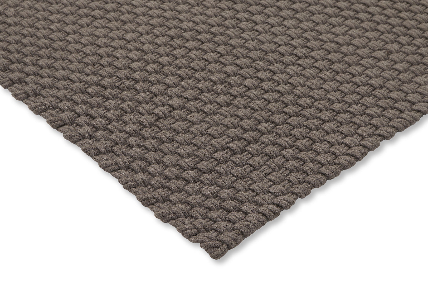 Corner view of the rug showing braided structure, stitched edge, and low-profile height

