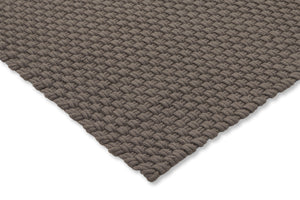 Corner view of the rug showing braided structure, stitched edge, and low-profile height

