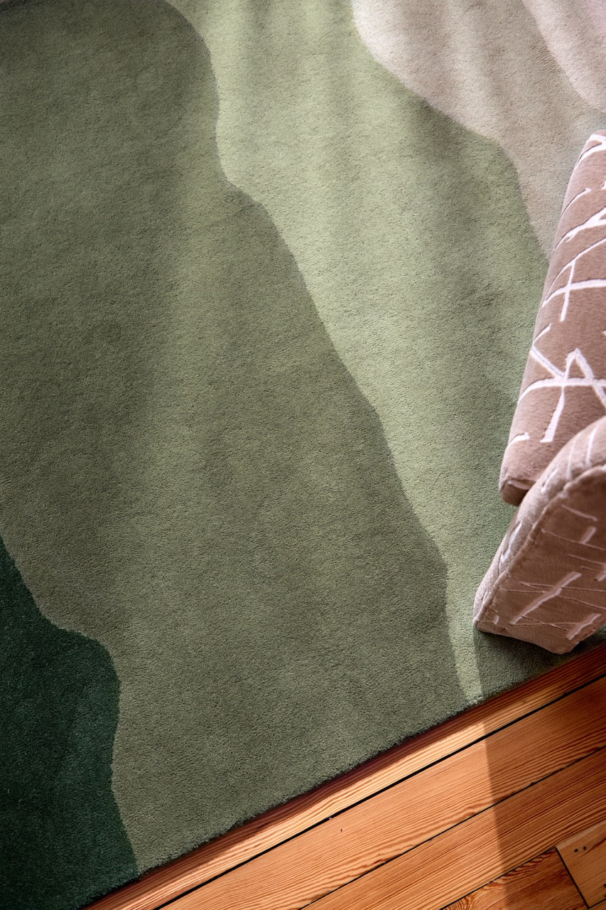 Harlequin Sedimentary Pine rug in pine green and sage, shown in an interior, third view