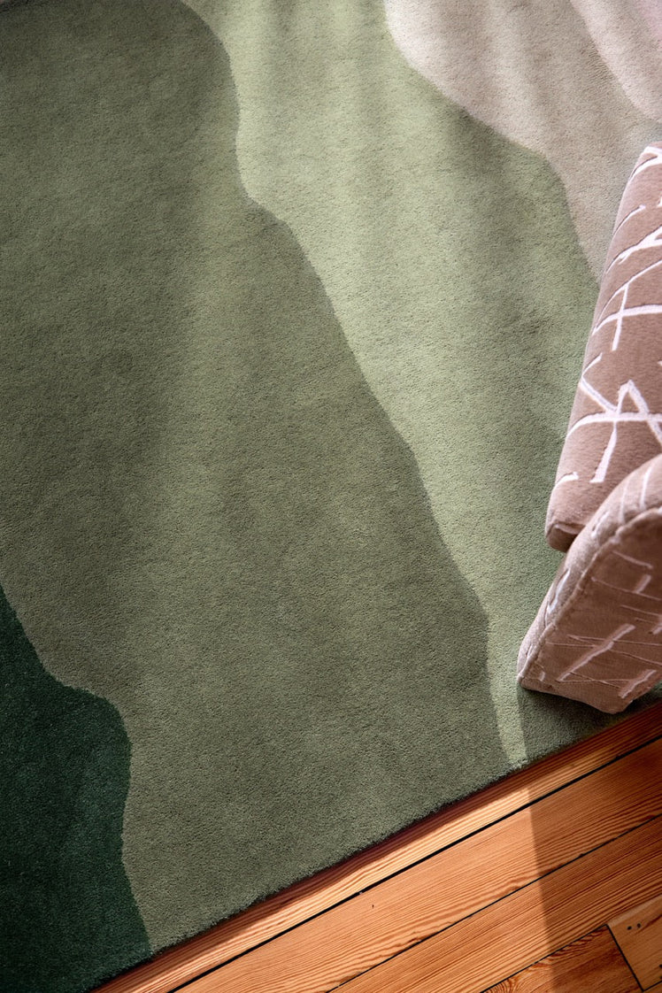 Harlequin Sedimentary Pine rug in pine green and sage, shown in an interior, third view