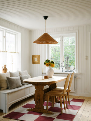 Layered Chess Flatweave Burgundy rug styled in a modern lounge with low beige armchairs and walnut accents

