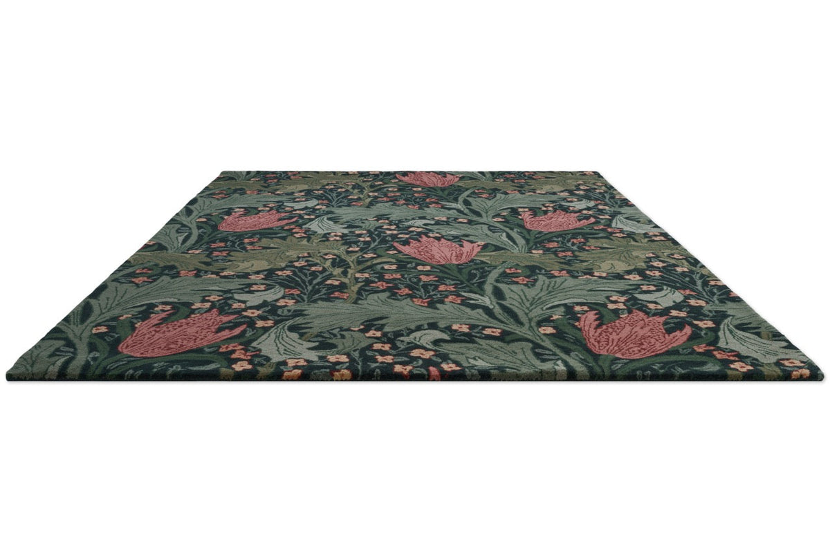 Morris & Co Lent Lily Indigo Madder rug in indigo with madder red tulips and sage leaves, perspective view