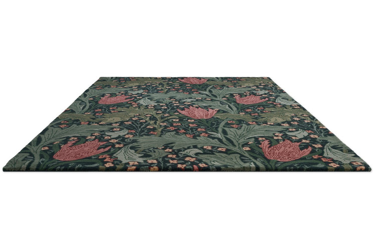 Morris & Co Lent Lily Indigo Madder rug in indigo with madder red tulips and sage leaves, perspective view