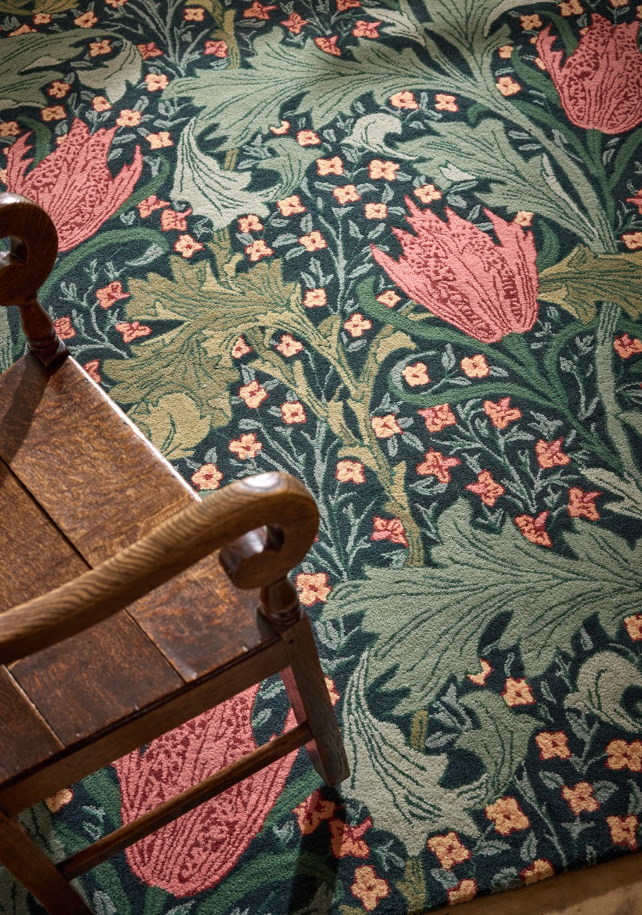 Morris & Co Lent Lily Indigo Madder rug in indigo with madder red tulips and sage leaves, shown in an interior, second view
