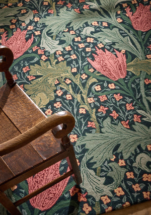 Morris & Co Lent Lily Indigo Madder rug in indigo with madder red tulips and sage leaves, shown in an interior, second view