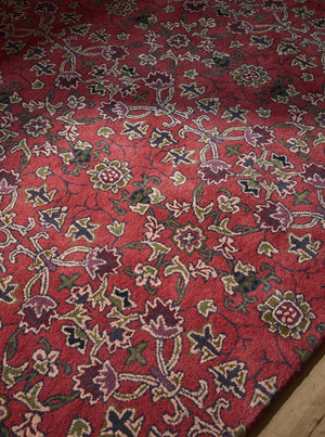 Morris & Co Persian Scroll Plum rug in warm red with cream, olive and aubergine, shown in an interior, third view