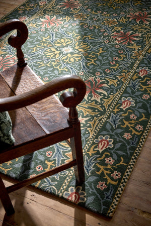 Morris & Co Walthamstow Forest Teal rug in forest green, teal and old gold, shown in an interior, second view