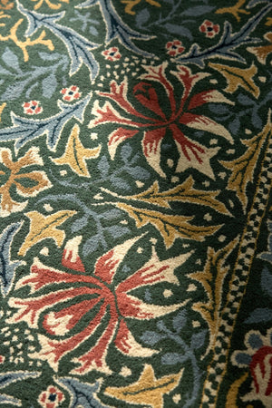 Morris & Co Walthamstow Forest Teal rug in forest green, teal and old gold, shown in an interior, third view