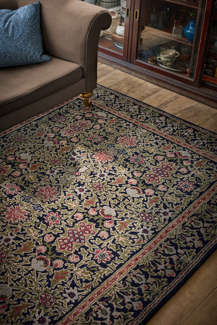 Morris & Co Wilton Weave Indigo rug in indigo, olive green and rose, shown in an interior, second view
