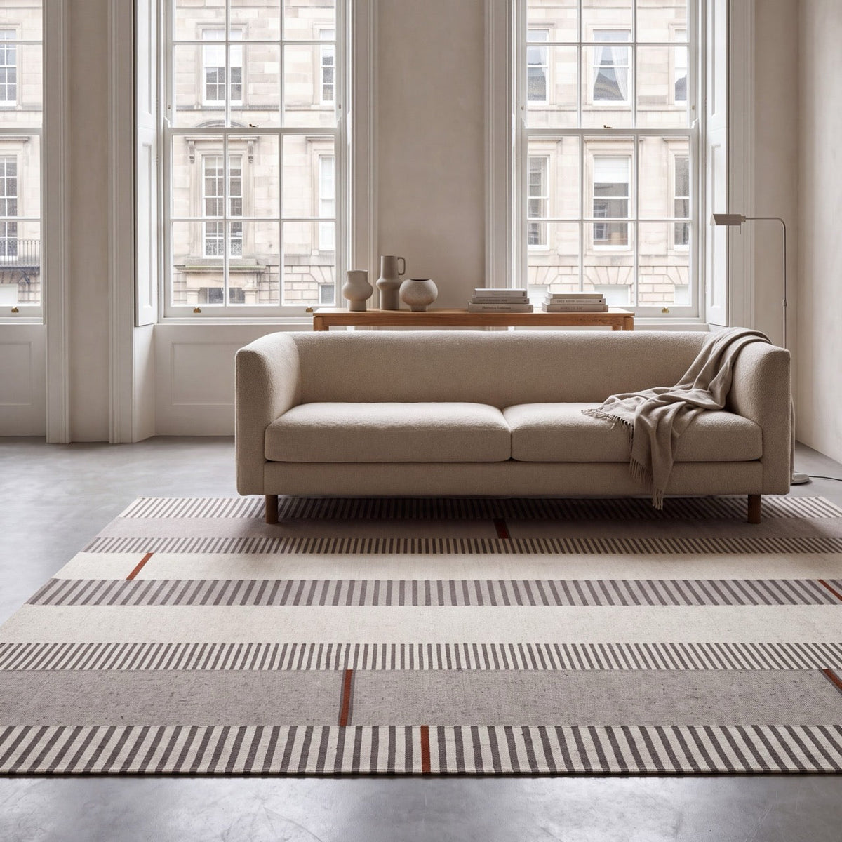 Acsento Oslo Grey Terra rug in grey with ivory and charcoal stripes and terracotta accents, shown in an interior, second view