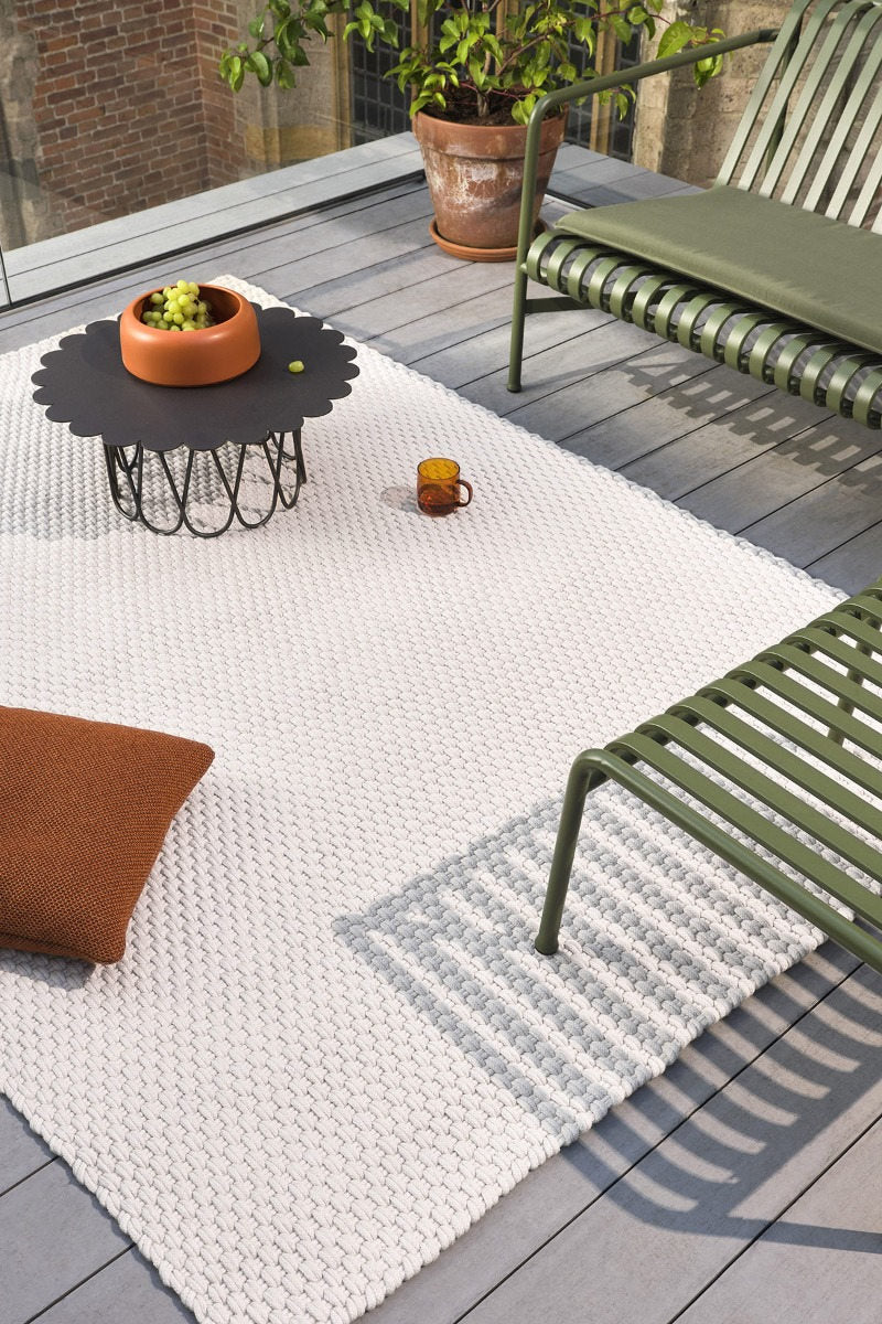 Brink & Campman Lace White Sand rug placed on a pale stone terrace with natural wood seating
