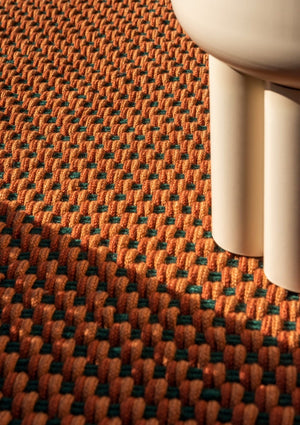 Close-up of recycled PET flatweave in warm rust, terra, and muted green stripe pattern

