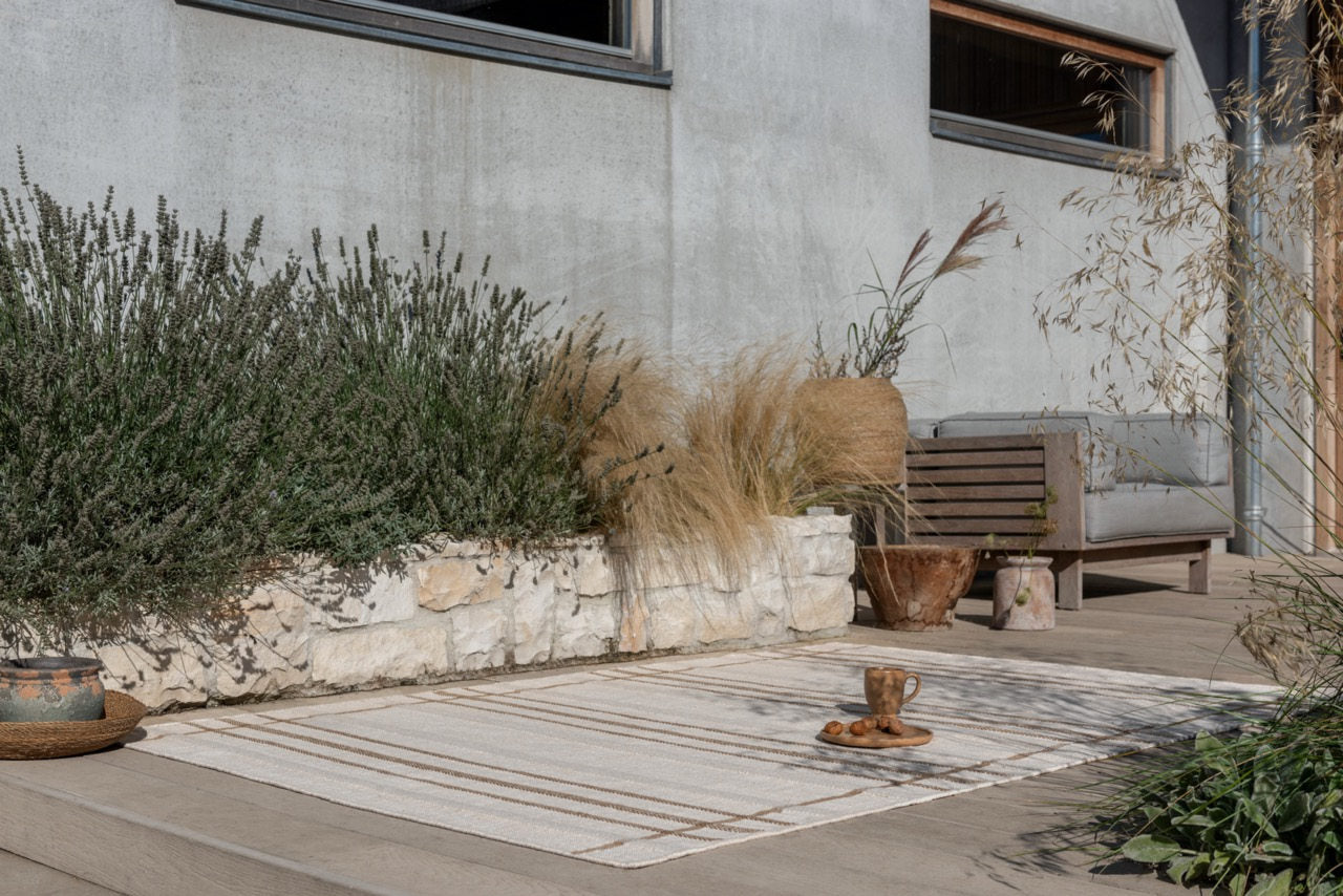 Zona Line Sesame rug styled in an outdoor seating area with wooden furniture